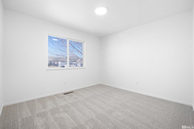 carpeted spare room featuring baseboards and visible vents