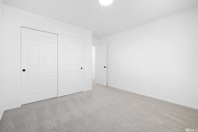 unfurnished bedroom with baseboards, a closet, and light colored carpet