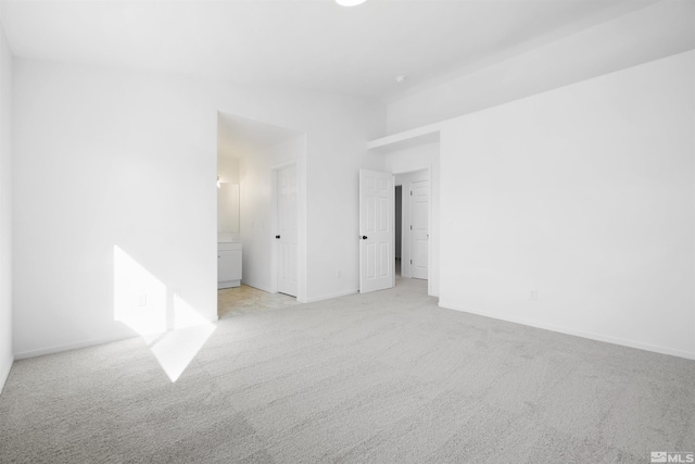 spare room featuring baseboards and light colored carpet