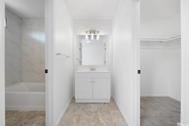 bathroom with baseboards, a walk in closet, and vanity