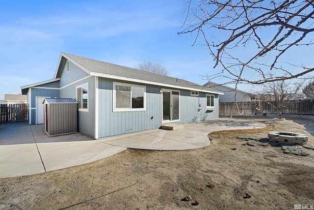 rear view of property featuring an outdoor fire pit, roof with shingles, a patio area, and a fenced backyard