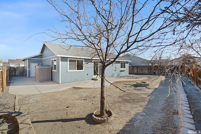 back of property with a shingled roof, an outdoor fire pit, a fenced backyard, and a patio