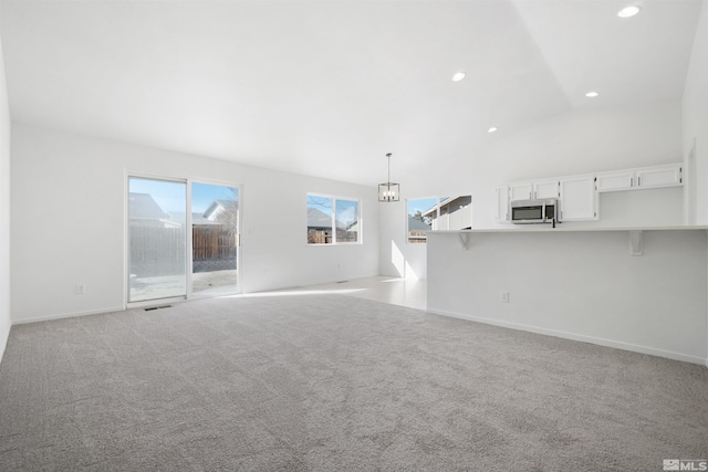 unfurnished living room with a notable chandelier, recessed lighting, visible vents, light colored carpet, and vaulted ceiling