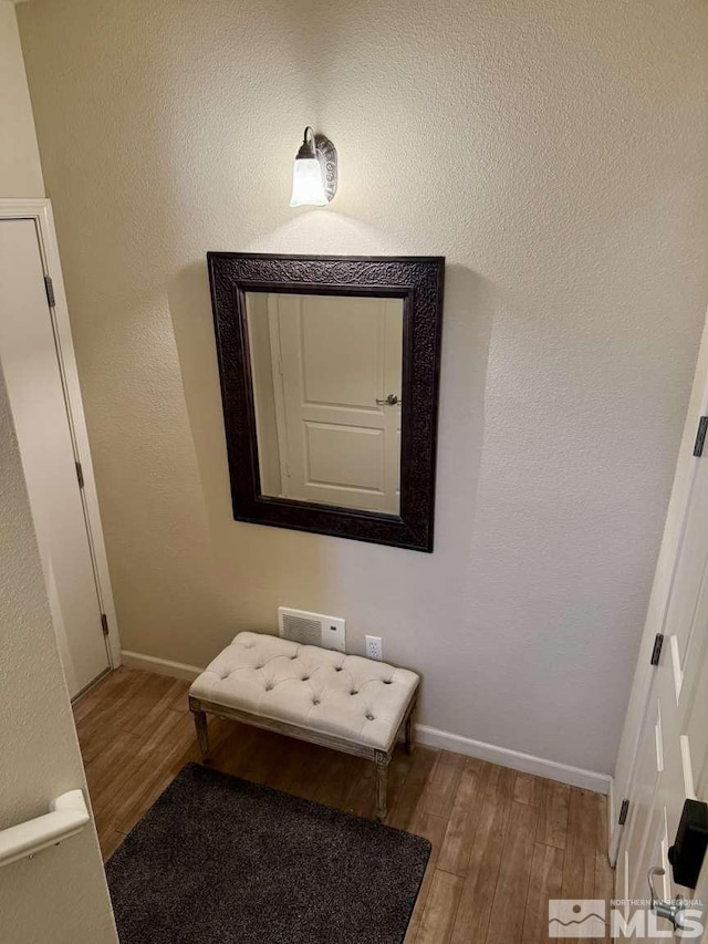 interior space featuring a textured wall, baseboards, and wood finished floors