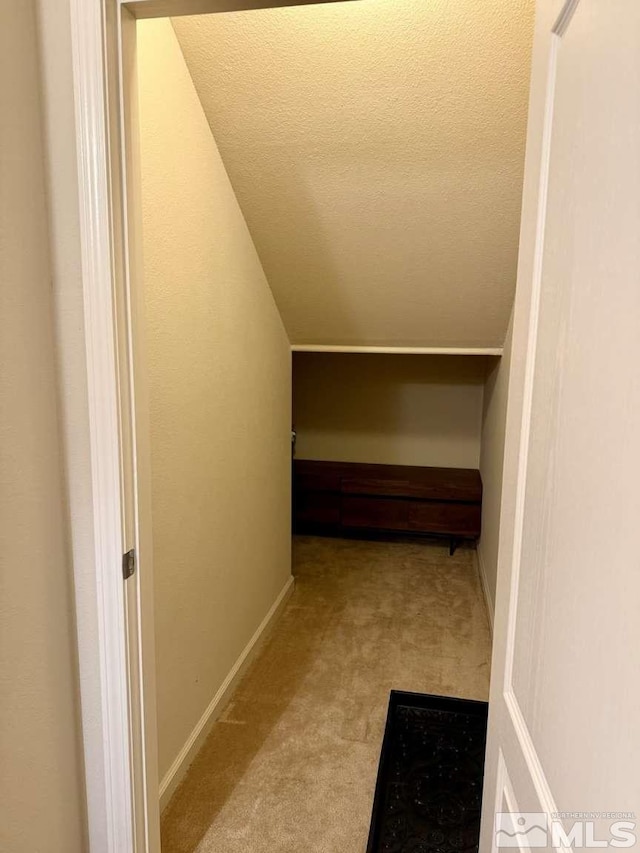 corridor with carpet, baseboards, and a textured ceiling