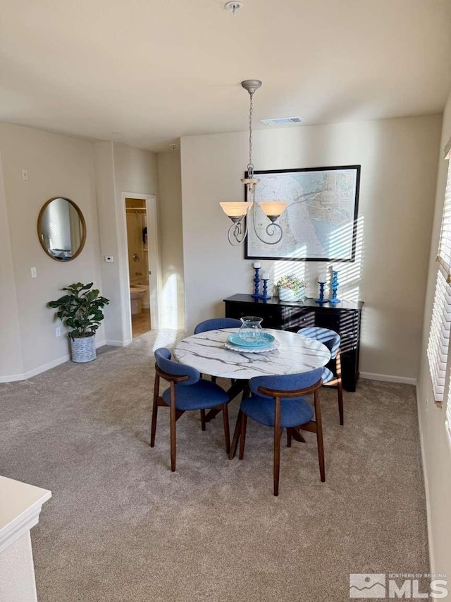 dining room featuring baseboards, visible vents, and light colored carpet