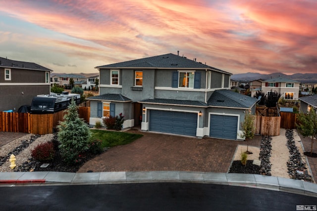 view of front of home featuring a garage, decorative driveway, fence, and a residential view