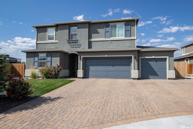 traditional-style home with decorative driveway, stucco siding, a front yard, fence, and a garage