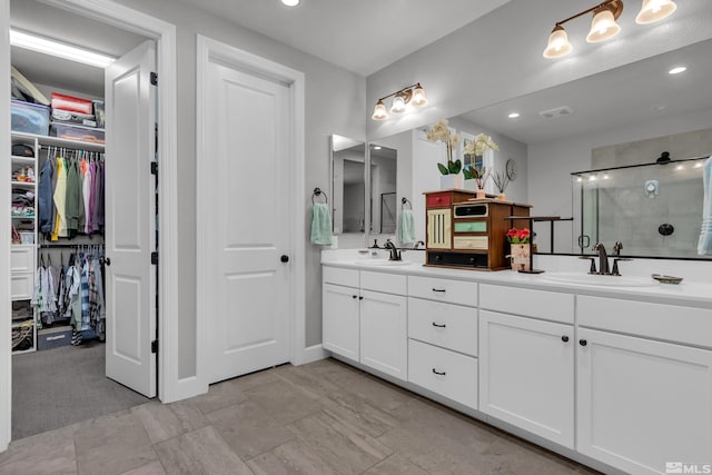 bathroom with double vanity, a stall shower, a walk in closet, and a sink