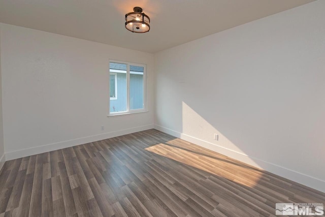 spare room featuring baseboards and dark wood finished floors