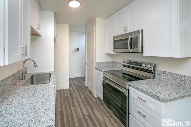 kitchen featuring appliances with stainless steel finishes, white cabinetry, a sink, and light stone counters