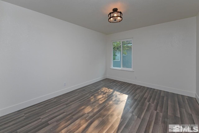 spare room with dark wood-style floors and baseboards