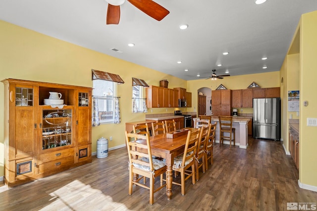 dining space featuring arched walkways, dark wood finished floors, a ceiling fan, and recessed lighting