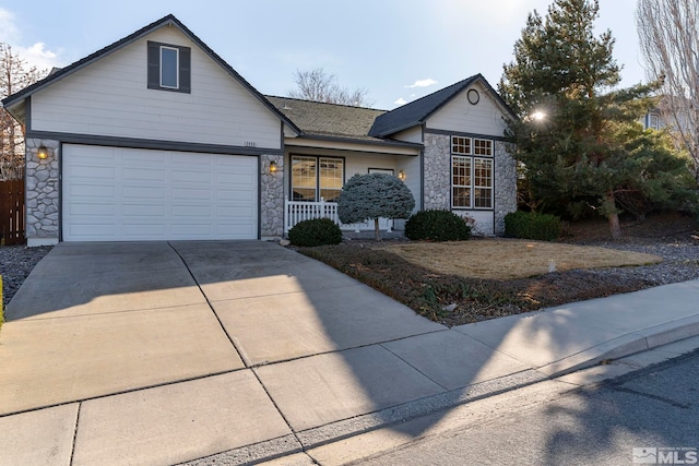 view of front of home featuring driveway, stone siding, a garage, and covered porch