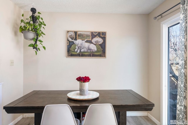 dining room featuring baseboards, breakfast area, a textured ceiling, and wood finished floors