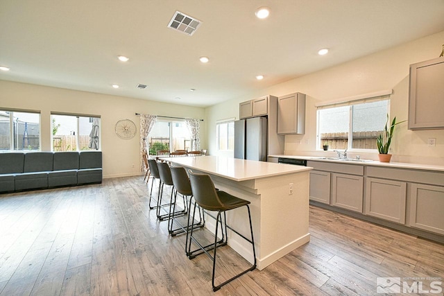 kitchen featuring freestanding refrigerator, gray cabinets, visible vents, and a kitchen bar