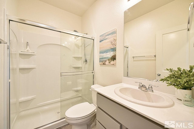 full bath featuring a stall shower, vanity, and toilet