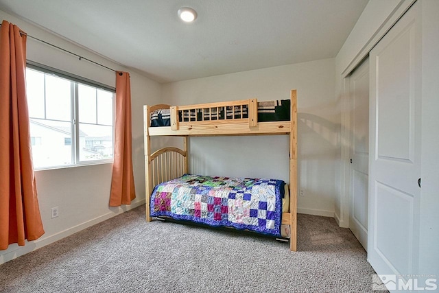 carpeted bedroom with a closet and baseboards