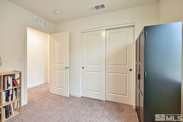 unfurnished bedroom featuring light colored carpet, a closet, visible vents, and baseboards