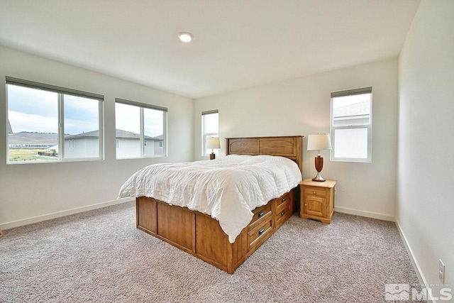 bedroom featuring light colored carpet and baseboards