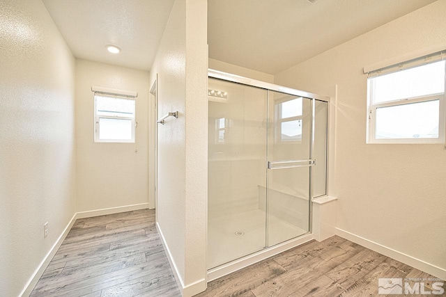 bathroom with a stall shower, baseboards, and wood finished floors