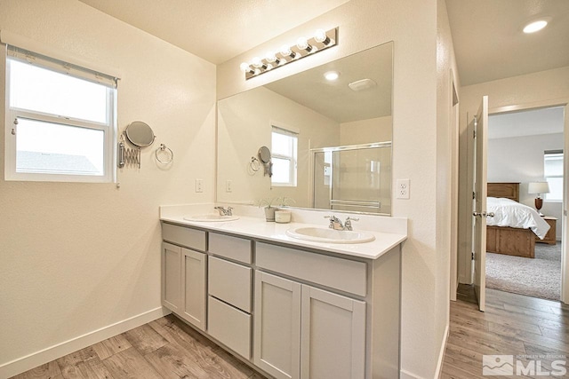 ensuite bathroom featuring wood finished floors, ensuite bath, a sink, and a stall shower