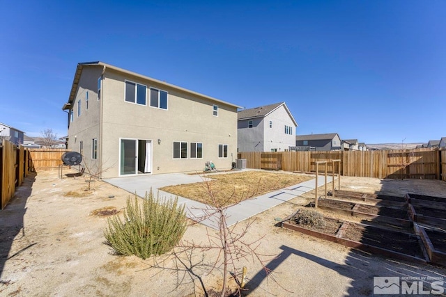 rear view of house featuring a vegetable garden, a patio, stucco siding, cooling unit, and a fenced backyard