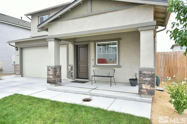 entrance to property with fence, concrete driveway, and stucco siding