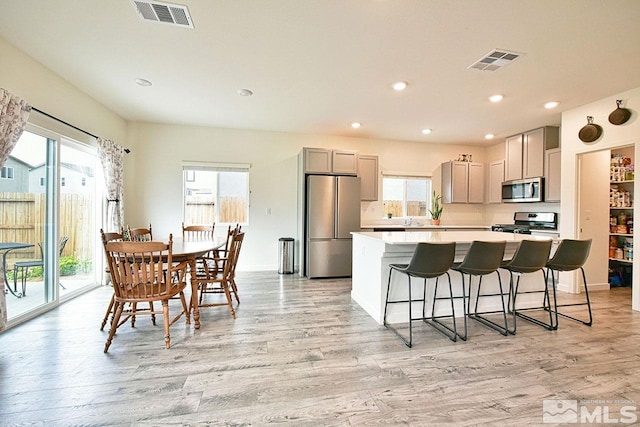 kitchen featuring appliances with stainless steel finishes, visible vents, a kitchen island, and gray cabinetry