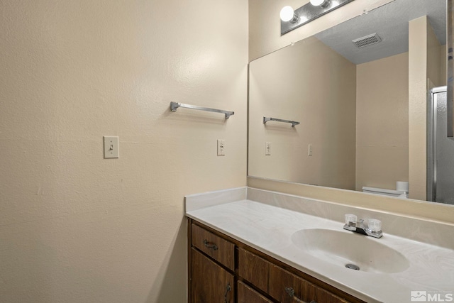 bathroom with toilet, visible vents, and vanity