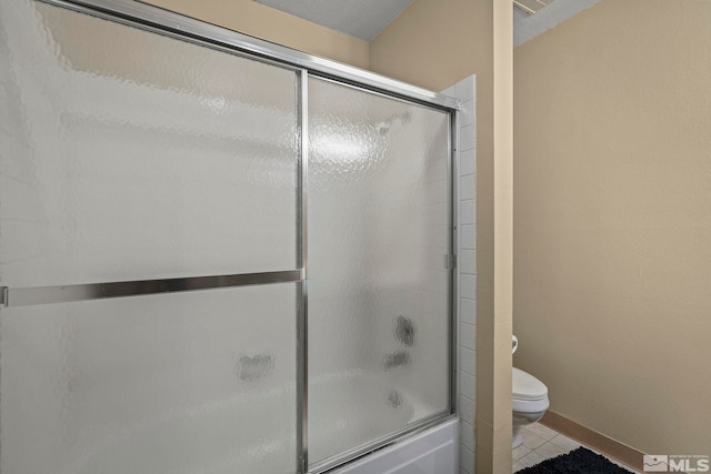 bathroom featuring toilet, shower / bath combination with glass door, and tile patterned flooring