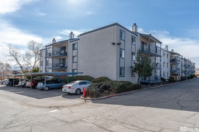 view of building exterior featuring covered and uncovered parking