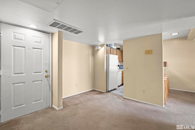 spare room with baseboards, visible vents, a textured ceiling, and light colored carpet