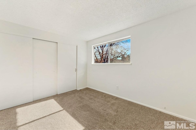 unfurnished bedroom featuring a textured ceiling, carpet floors, and a closet