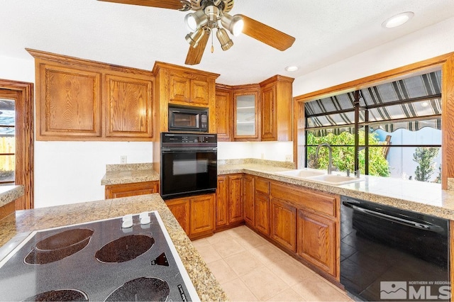 kitchen with brown cabinets, glass insert cabinets, a healthy amount of sunlight, a sink, and black appliances