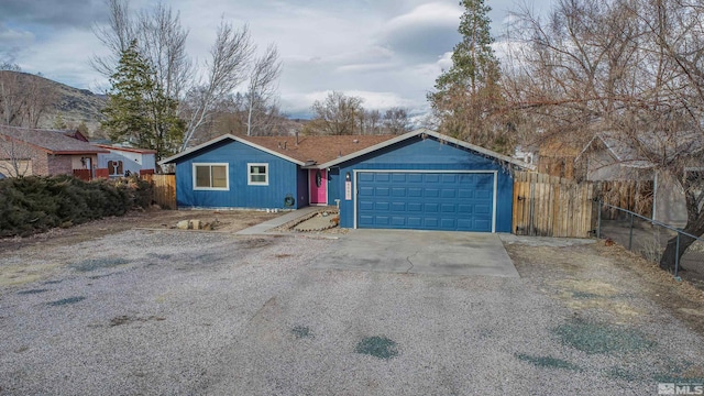 view of front of house with concrete driveway, an attached garage, and fence