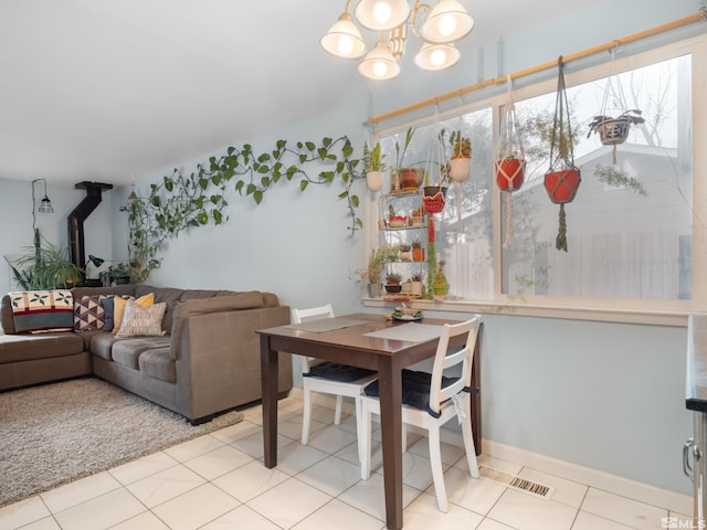 dining room with a wood stove, light tile patterned floors, visible vents, and a chandelier