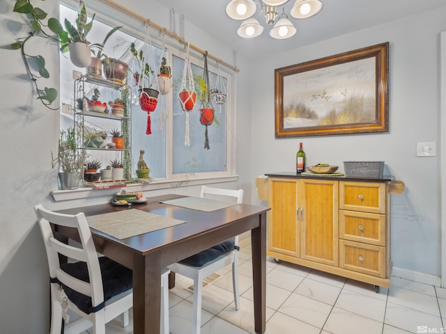 dining room with marble finish floor, a notable chandelier, and baseboards