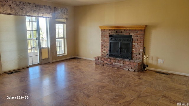 unfurnished living room featuring a brick fireplace, visible vents, and baseboards