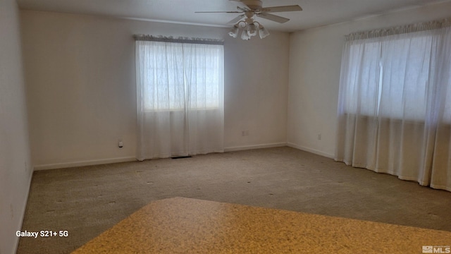 unfurnished room with visible vents, carpet, a ceiling fan, and baseboards