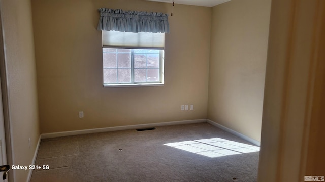 spare room with carpet, visible vents, and baseboards