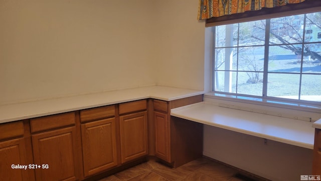 kitchen featuring dark tile patterned floors, brown cabinetry, and light countertops