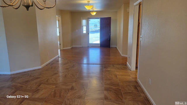 doorway featuring baseboards and an inviting chandelier