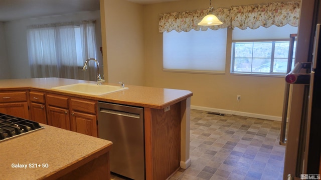 kitchen with brown cabinets, light countertops, appliances with stainless steel finishes, a sink, and baseboards