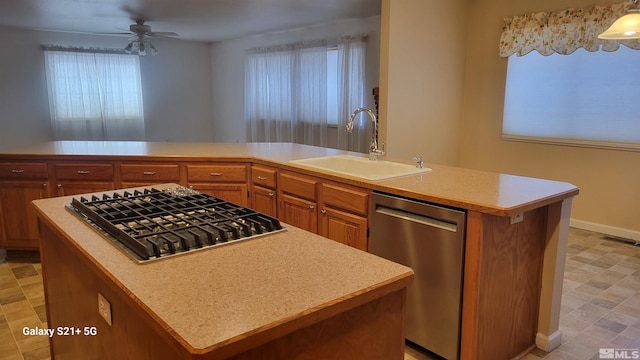 kitchen with stainless steel appliances, light countertops, a sink, and a kitchen island with sink