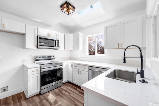 kitchen featuring white cabinets, light stone countertops, stainless steel appliances, and a sink