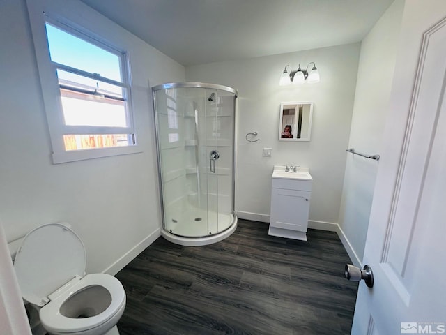 bathroom featuring wood finished floors, a shower stall, vanity, and baseboards