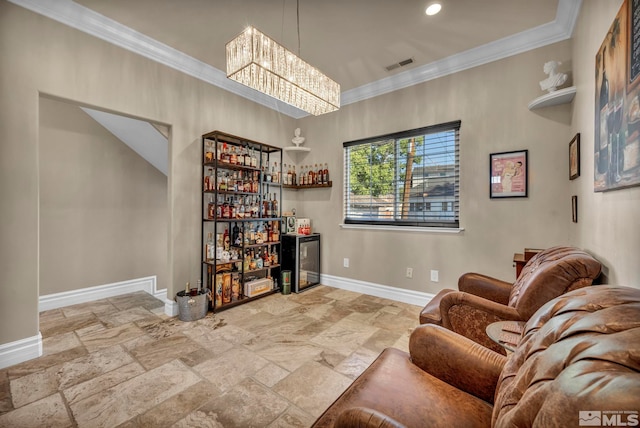 sitting room with visible vents, baseboards, stone finish flooring, a dry bar, and crown molding