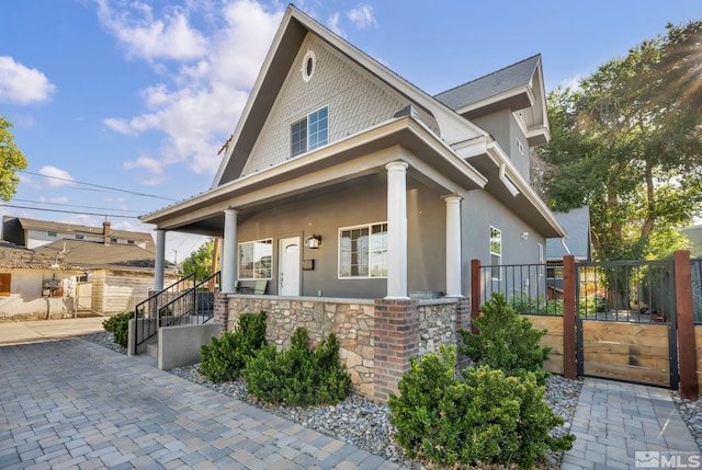 view of front of house featuring stone siding, covered porch, and stucco siding