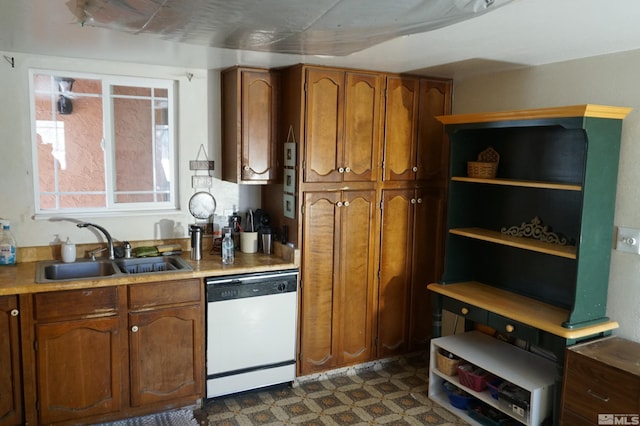 kitchen with brown cabinetry, dark floors, dishwasher, and a sink